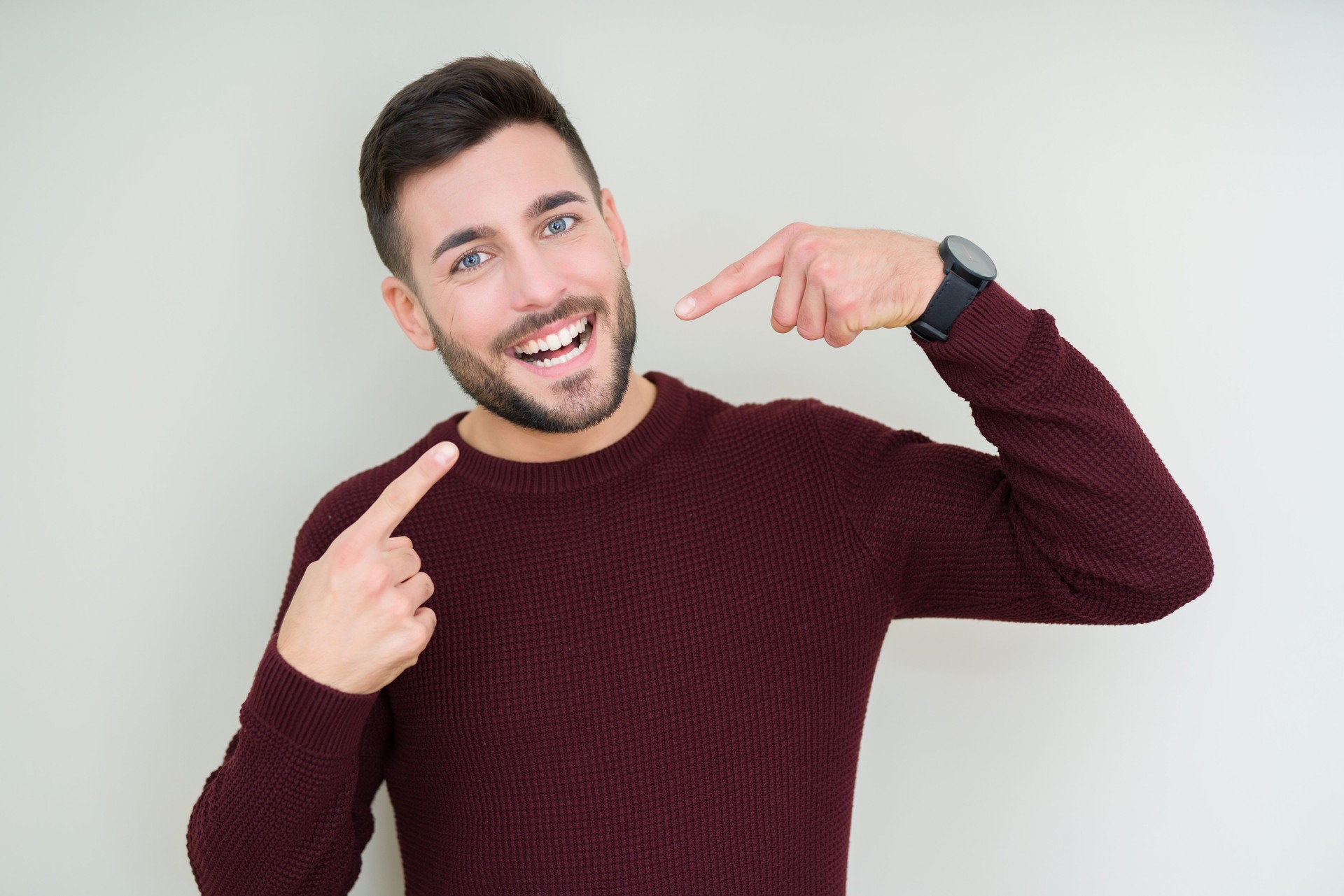 Young handsome man wearing a sweater over isolated background smiling confident showing and pointing with fingers teeth and mouth. Health concept.