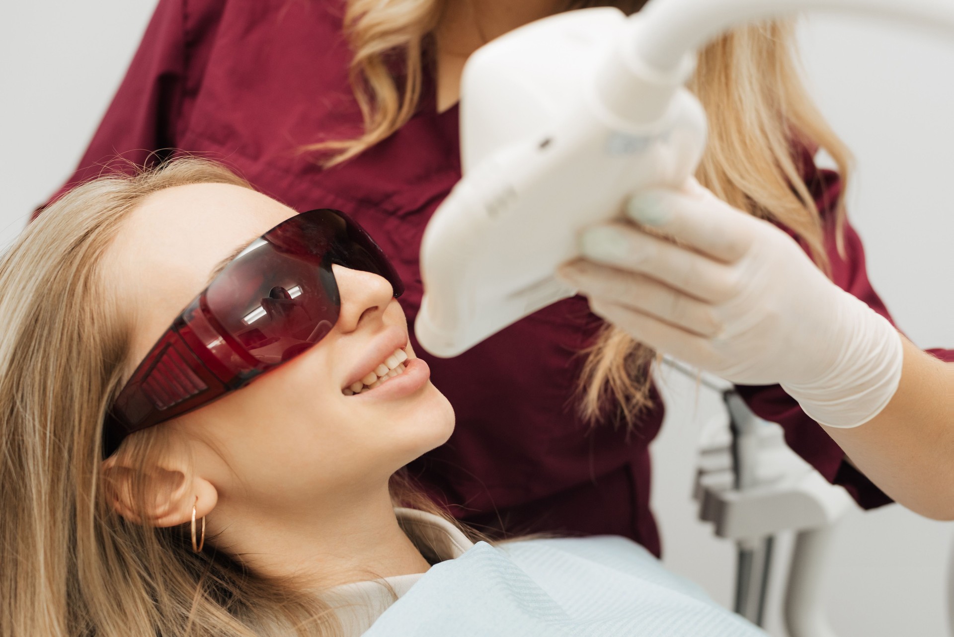Teeth whitening procedure with ultraviolet light UV lamp. Close-up portrait of a female patient at dentist in the clinic.